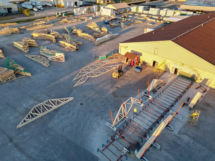 Aerial view of a truss plant yard with finished roof trusses and assembly tables