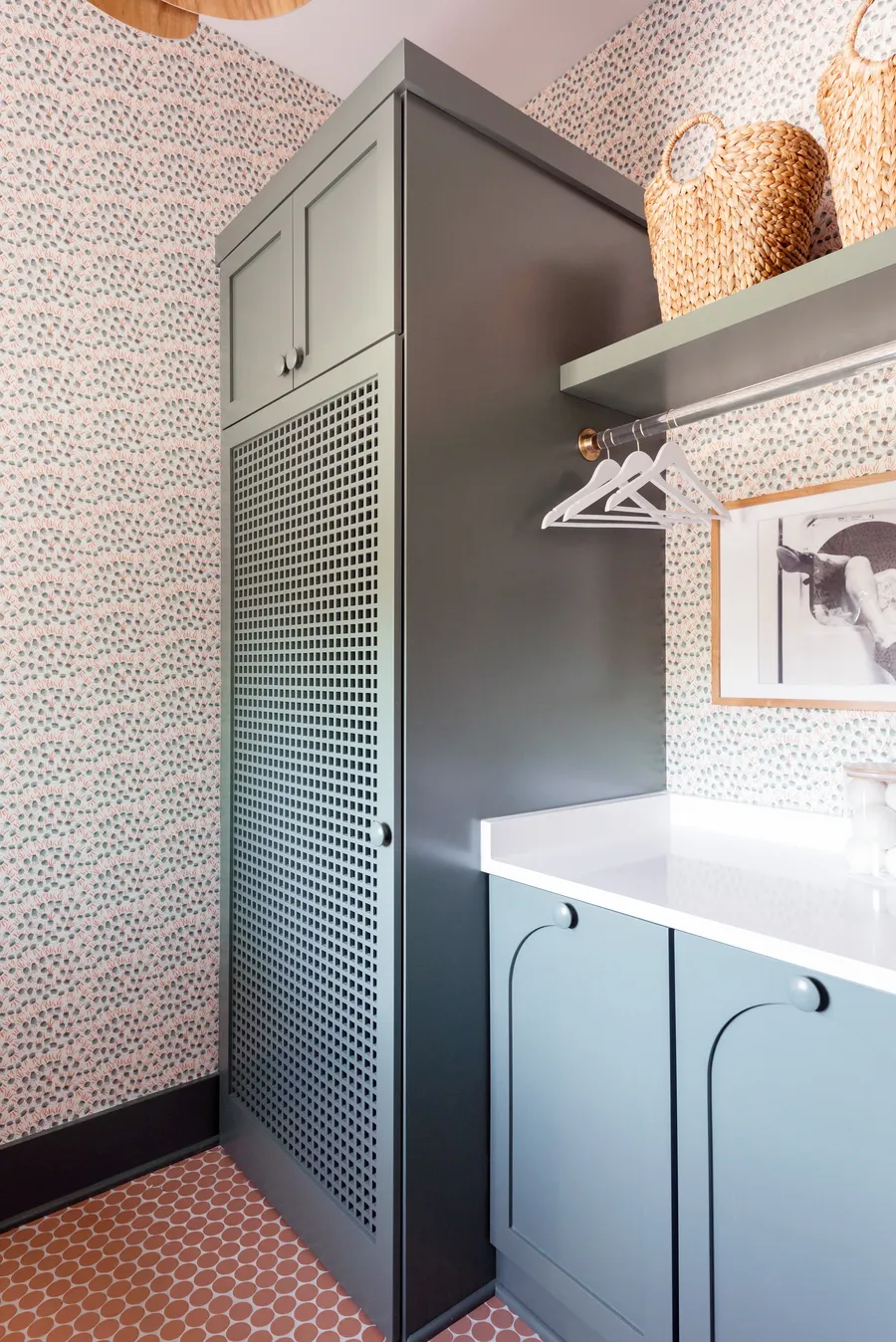 Laundry room with green cabinets, mesh-door tall cabinet, hanging rod and patterned wallpaper