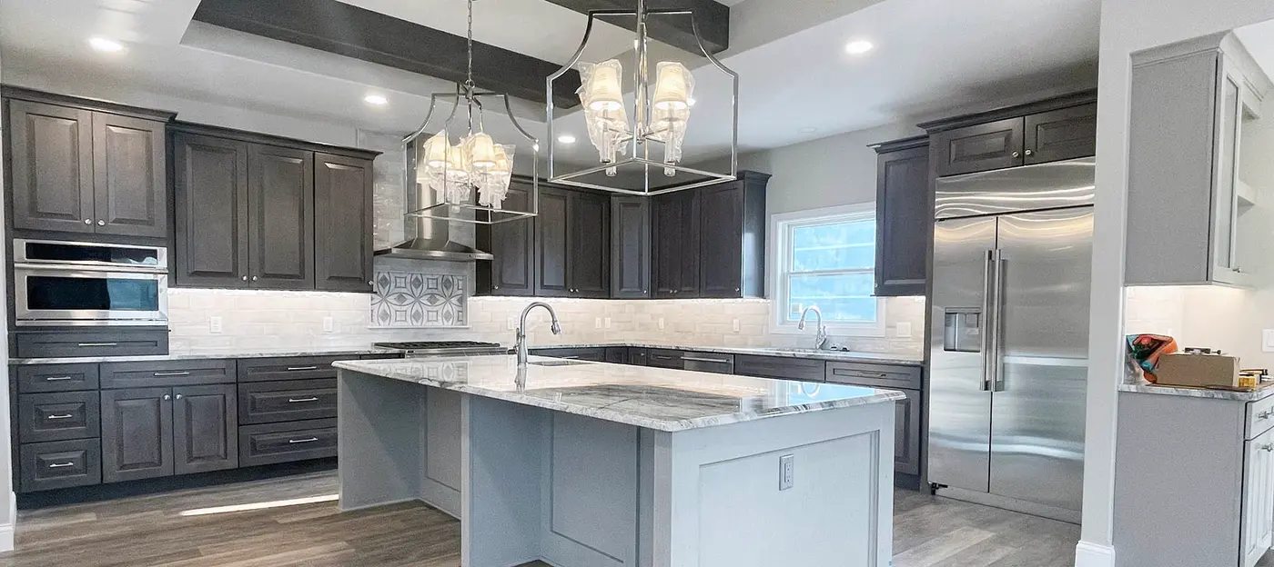 Gray kitchen with dark cabinets, stone-topped island and crystal lantern chandeliers
