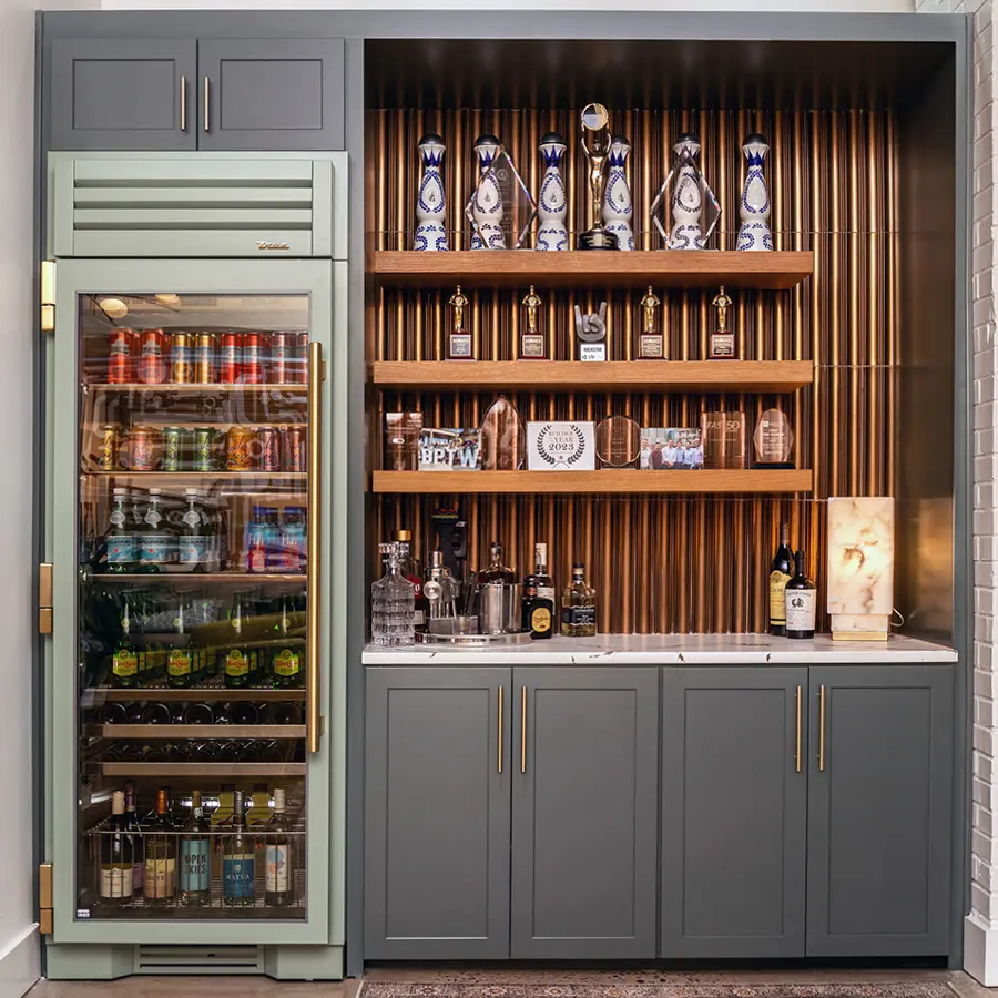 Built-in bar with gray cabinets, glass-front beverage fridge and lit display shelves