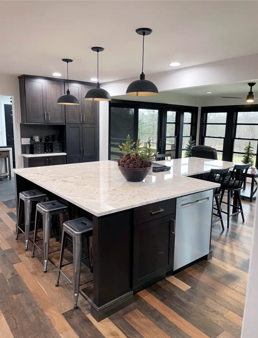 Large island with white stone top, dark cabinets, metal stools and black dome pendants