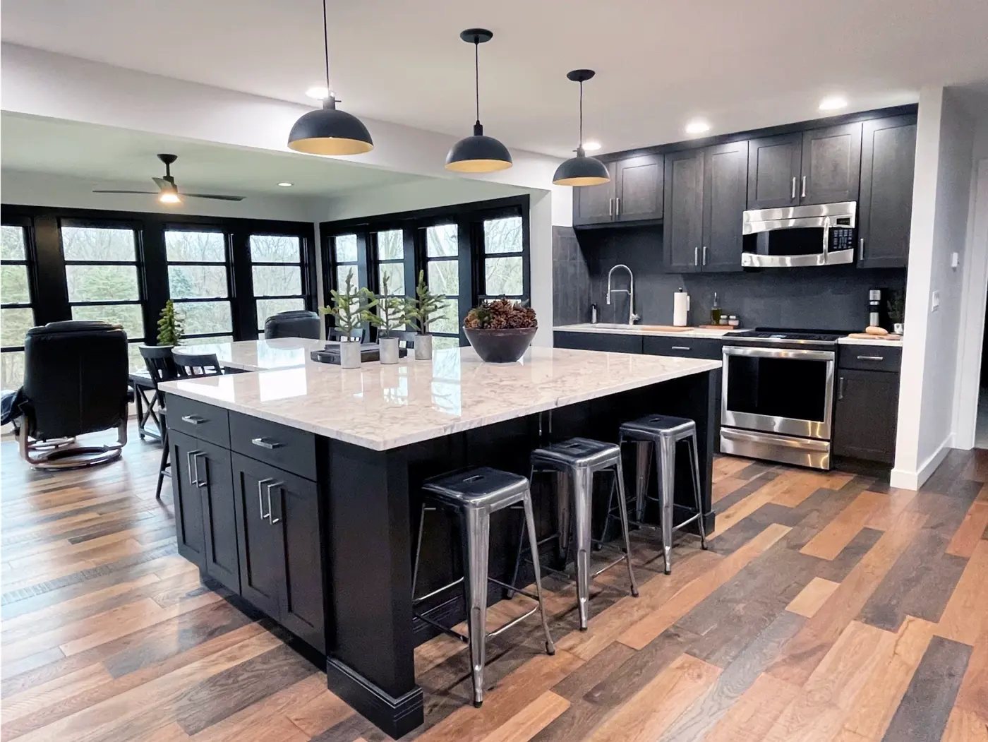 Kitchen with black cabinets, granite island, metal stools and dome pendants