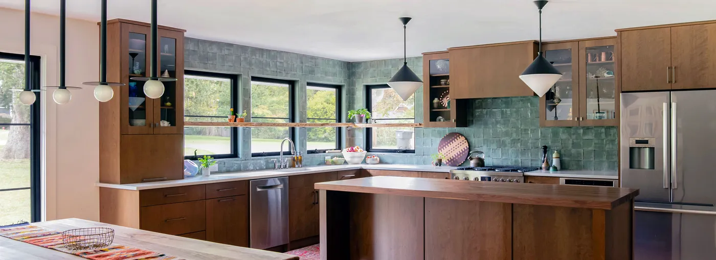 Kitchen with wood cabinets, green tile backsplash, island and globe pendant lights