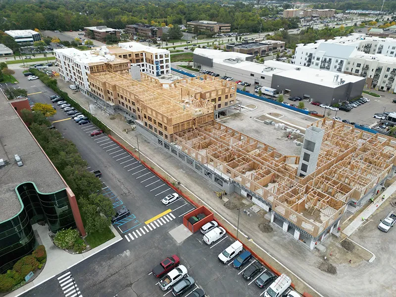 Aerial view of a multi-story wood-framed apartment building under construction in a city