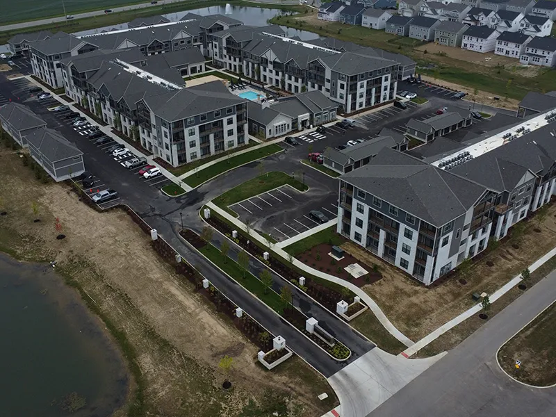 Aerial view of a completed apartment community with a pool beside a pond