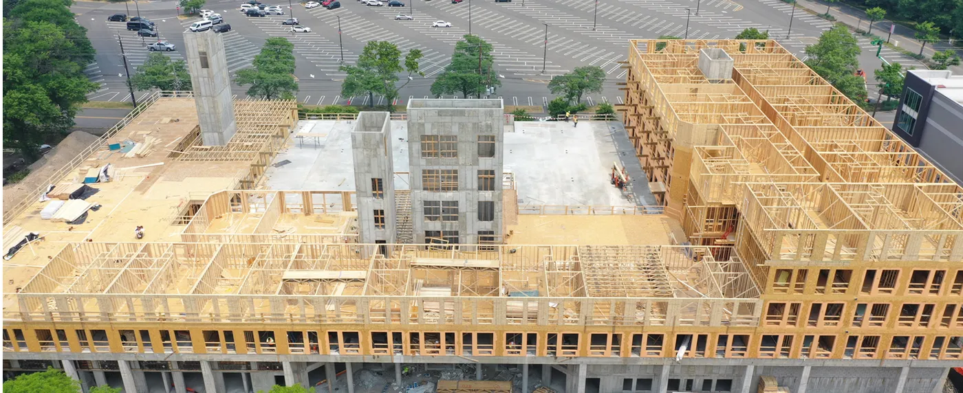 Aerial view of a large multi-story wood-framed building rising over a concrete podium
