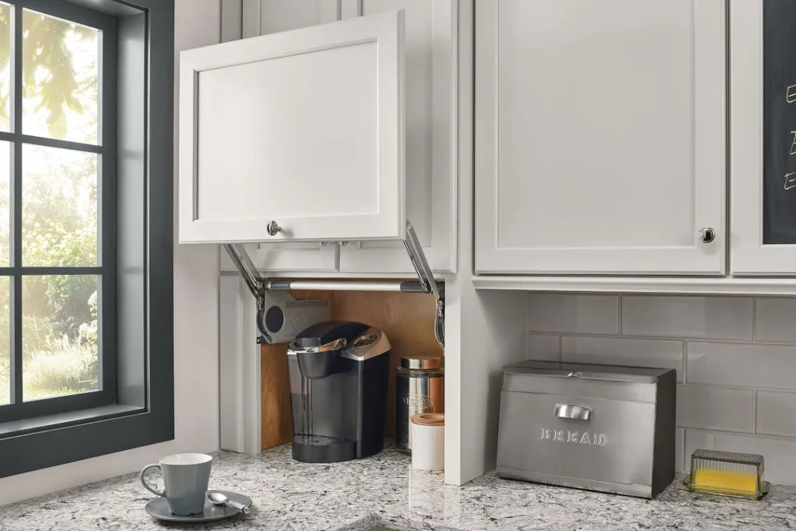 Lift-up cabinet door revealing a coffee maker in an appliance garage