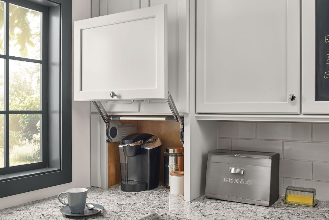 Lift-up cabinet door revealing a coffee maker in an appliance garage
