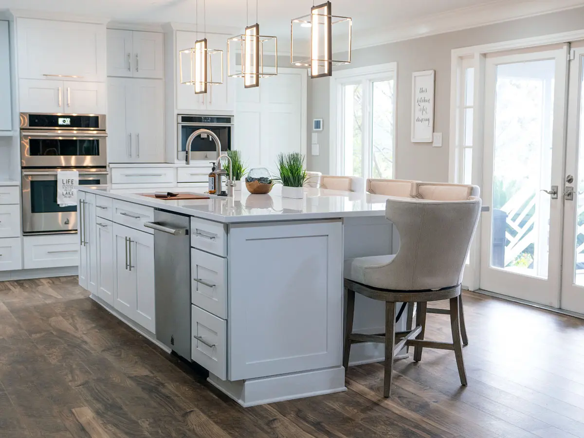 White kitchen with shaker cabinets, large island with bar stools and lantern pendants