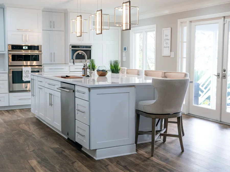 White kitchen with shaker cabinets, large island with bar stools and lantern pendants