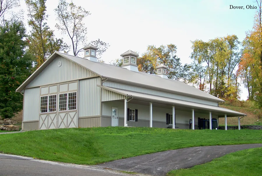 Pole barn with metal siding, cupolas and a long covered porch