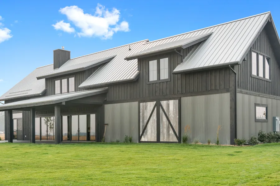 Barndominium with dark board-and-batten siding, metal roof and sliding barn doors