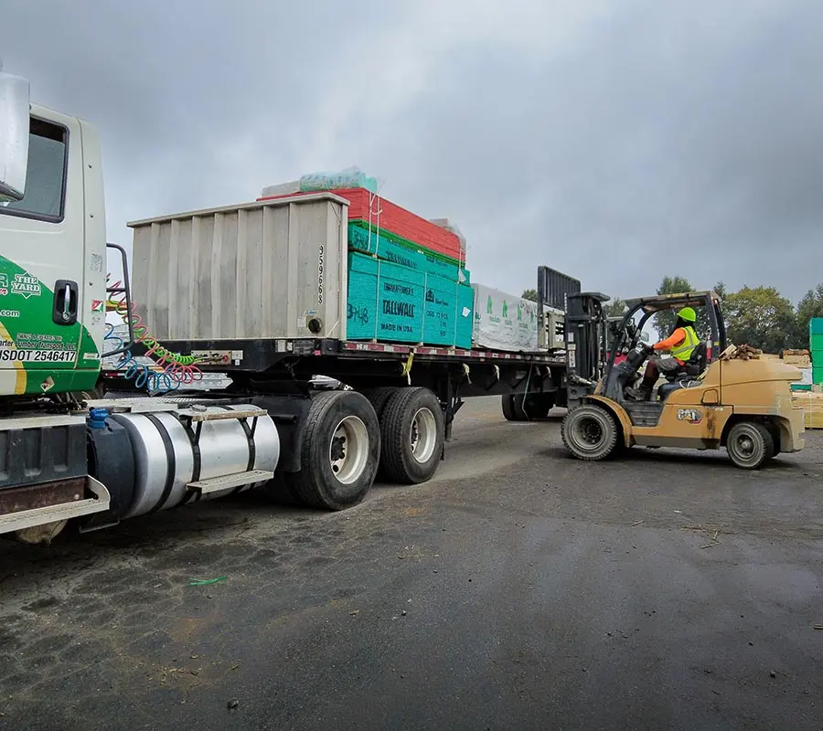 Forklift unloading building materials from a flatbed delivery truck