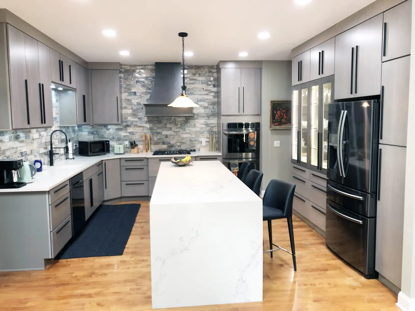 Gray flat-panel kitchen with stacked stone backsplash and white waterfall island