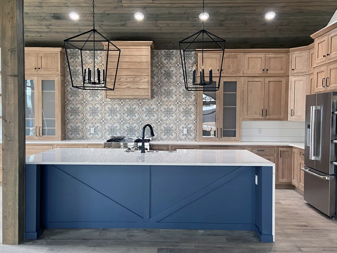 Blue island with X-panel sides facing natural wood cabinets and patterned tile wall