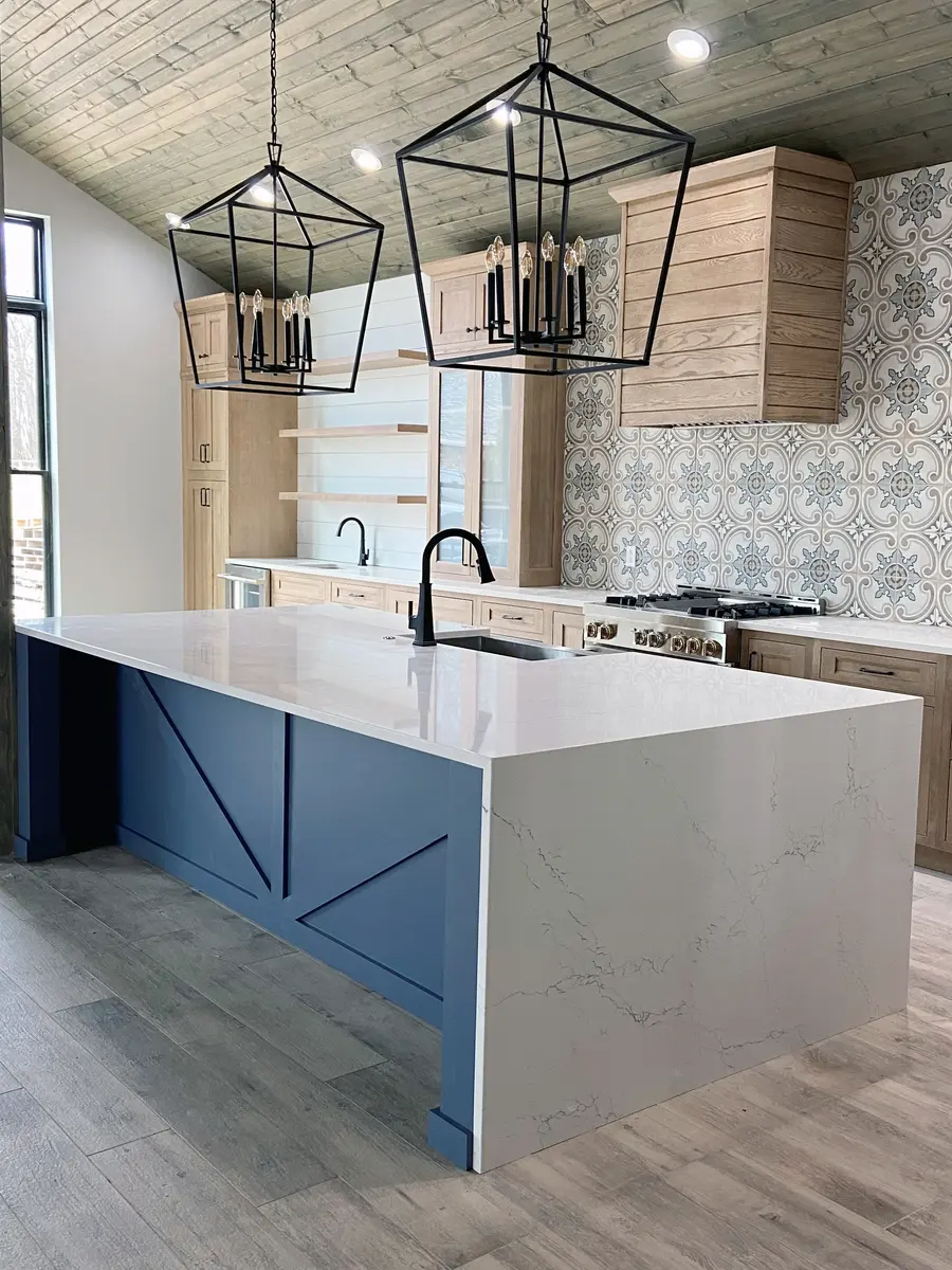 Blue island with waterfall stone edge under black lantern pendants and patterned tile